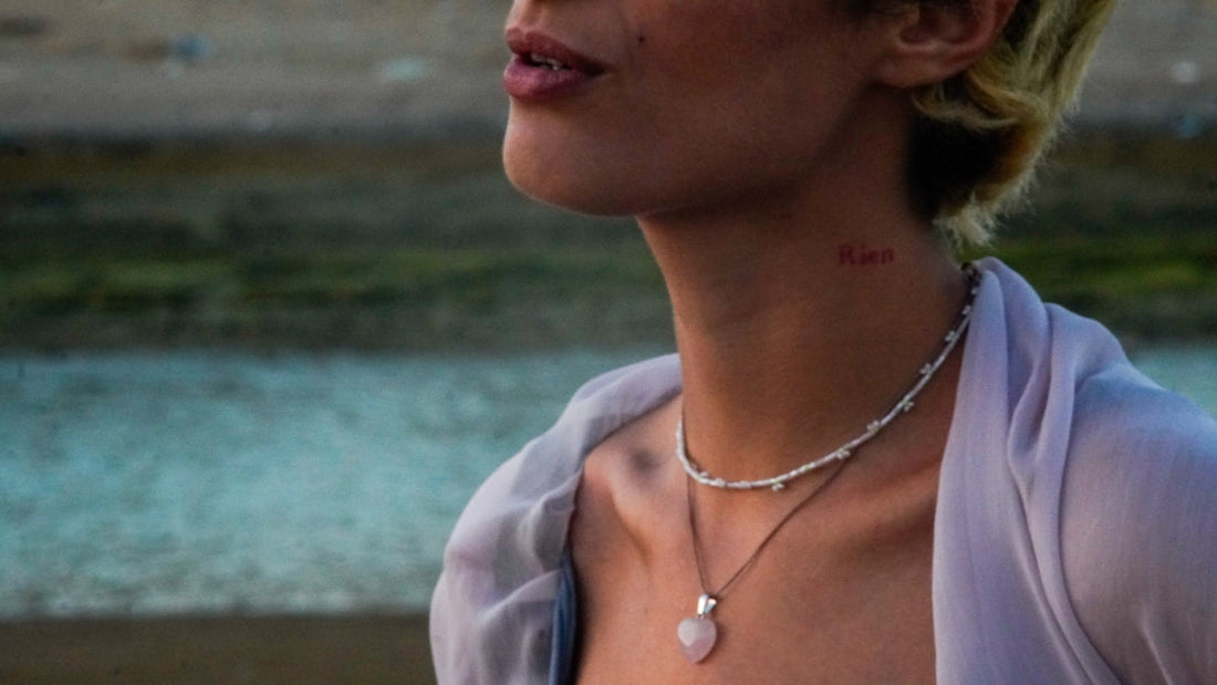 A woman displays jewelry and a neck tattoo.